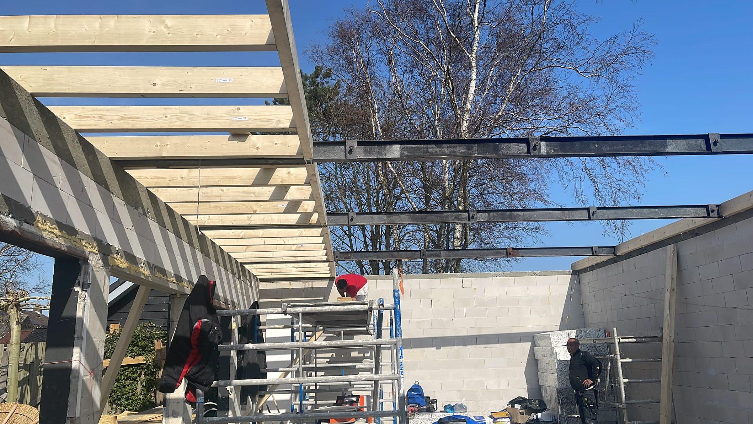 Dakconstructie in aanbouw: houten balken en stalen liggers.