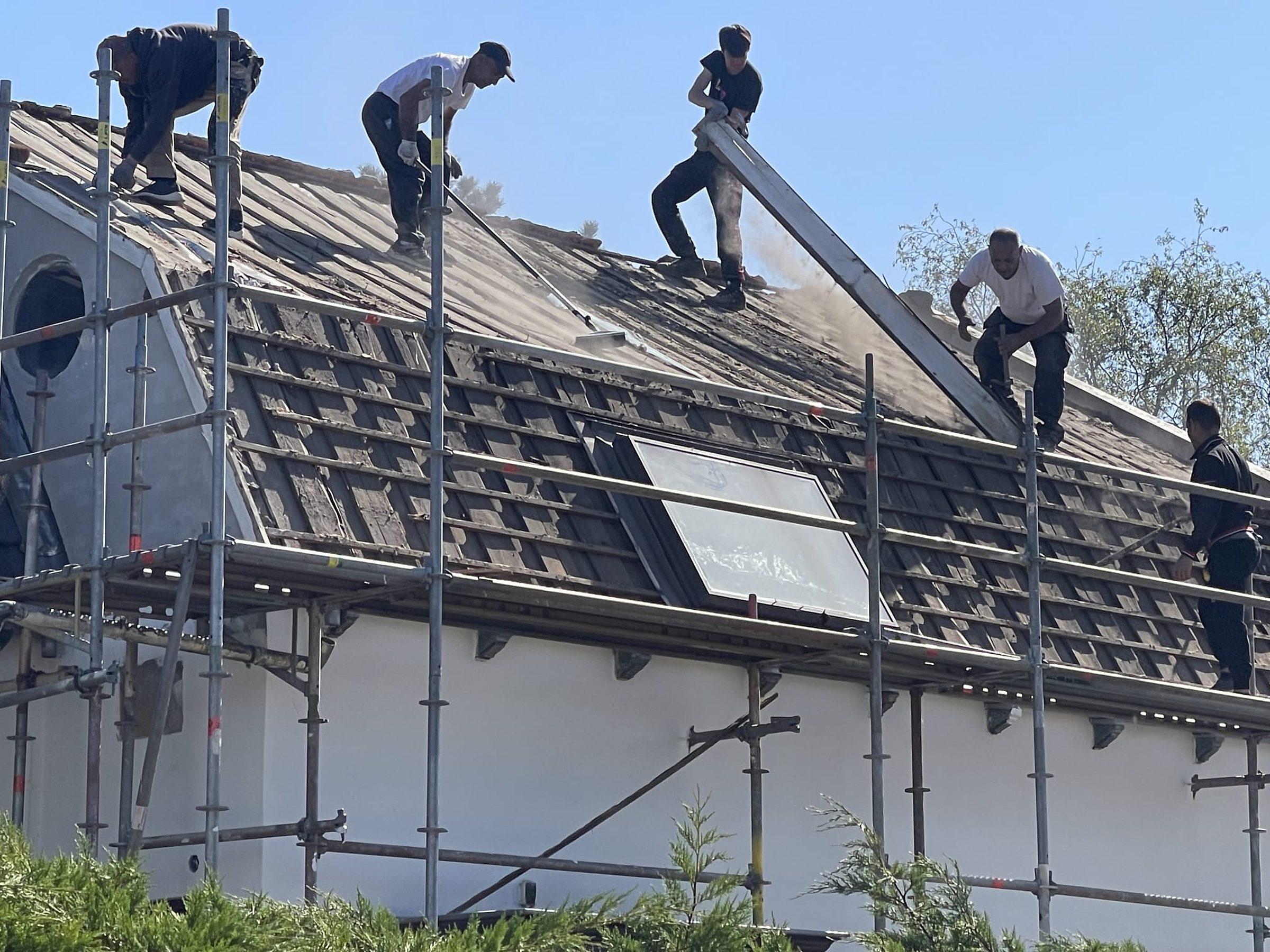 Dakdekkers leggen nieuwe dakpannen.