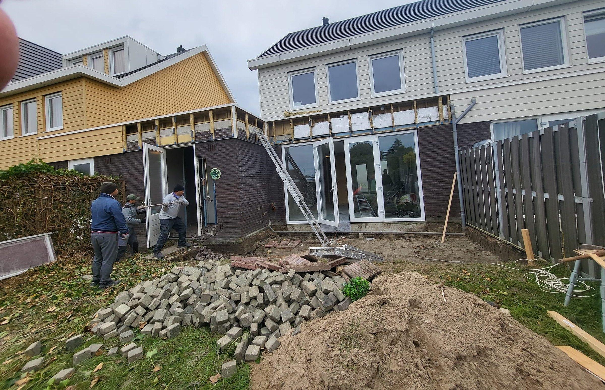 Aanbouw in wording aan een rijtjeswoning, steensopbouw en montage van het kozijn.
