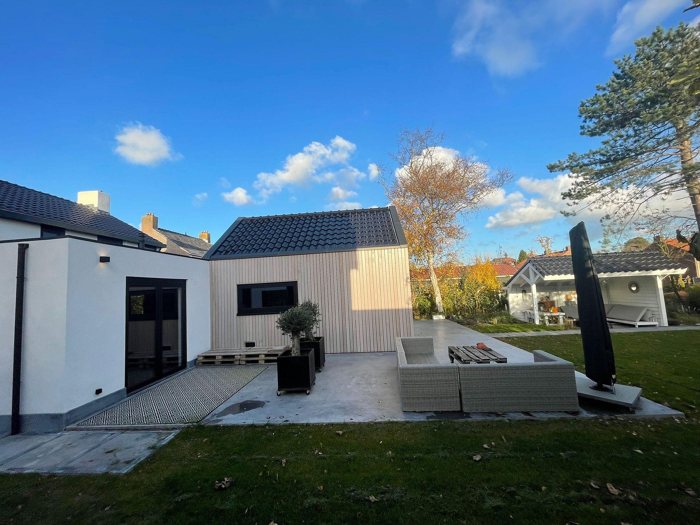 Afgeronde aanbouw met openslaande deuren, gezien vanuit de tuin.